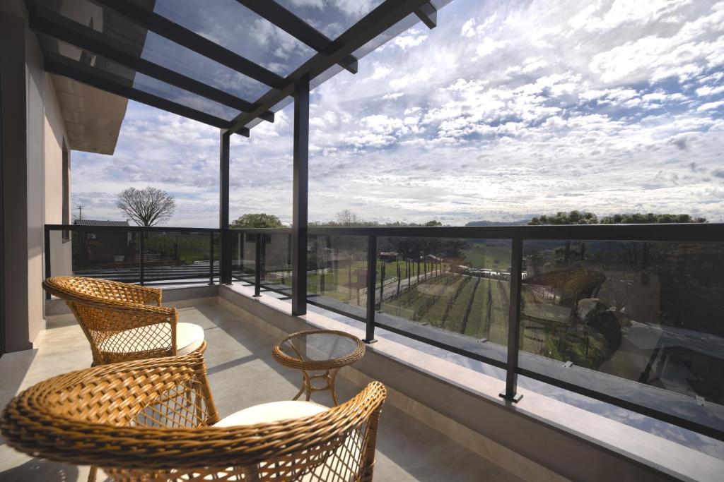 a balcony with wicker chairs and a large window at Pousada Premium Terragnolo in Bento Gonçalves