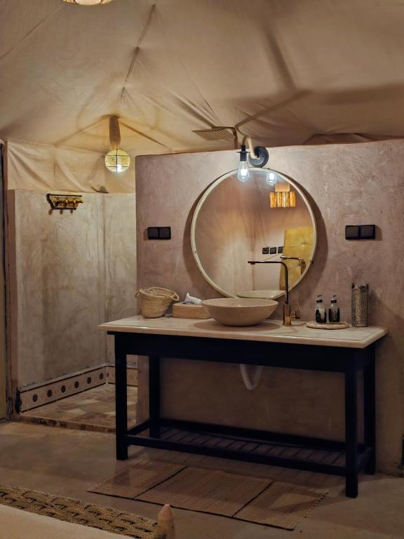 a bathroom with a sink and a mirror on a table at Kidal Luxury Camp in Adrouine