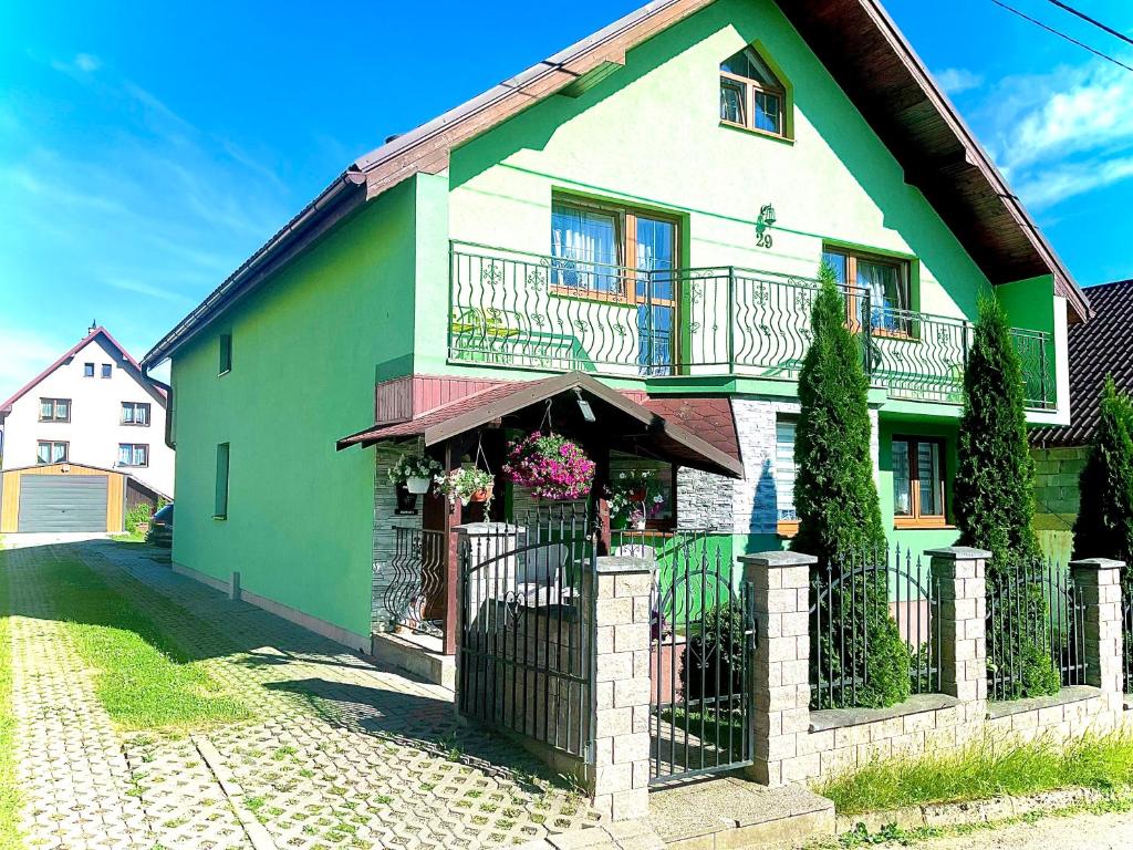 a green and white house with a fence at Homestay Renata in Nová Lesná