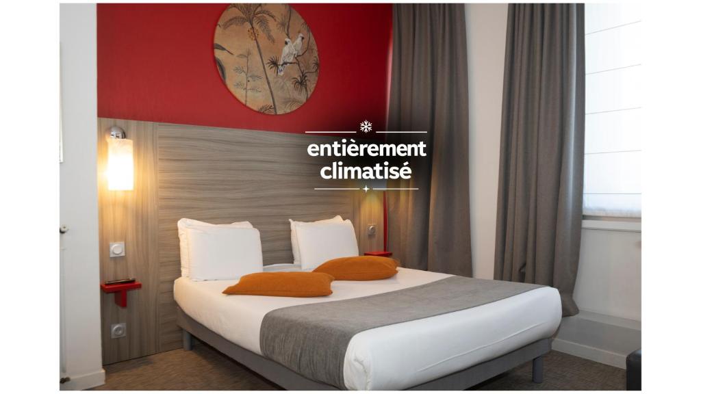 a bed with orange pillows in a hotel room at Hôtel de Champagne in Angers