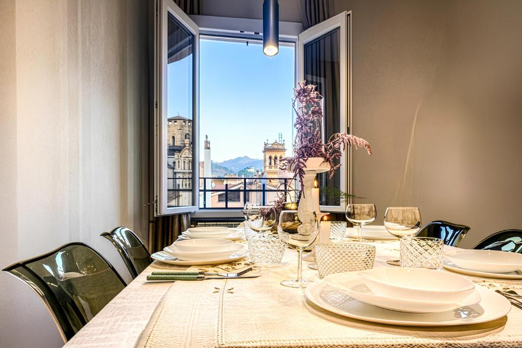 a table with plates and wine glasses and a window at Signature Design & Panoramic Views in Montecatini Terme