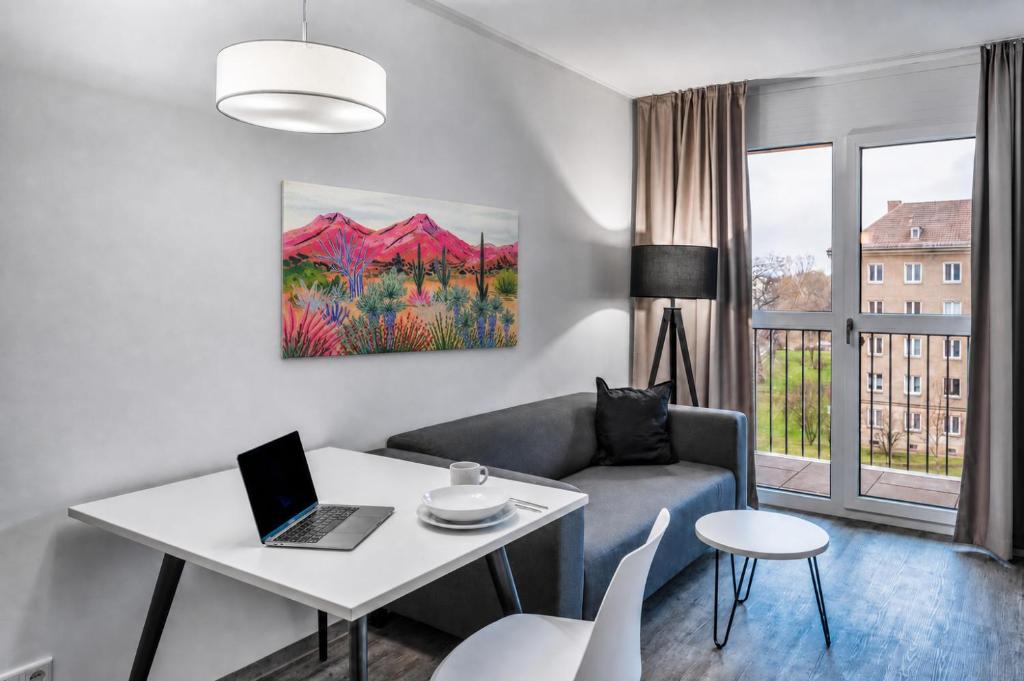 a living room with a couch and a table with a laptop at MIILOX Apartments Dresden in Dresden