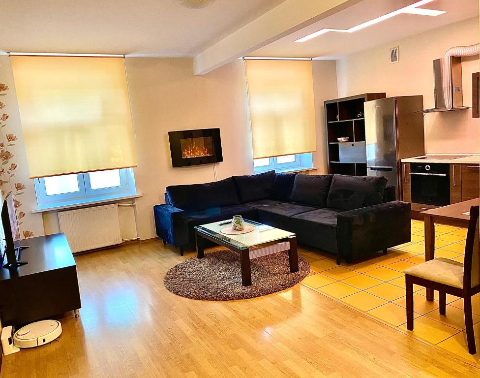 a living room with a black couch and a table at Klaipeda City Center Aparment in Klaipėda