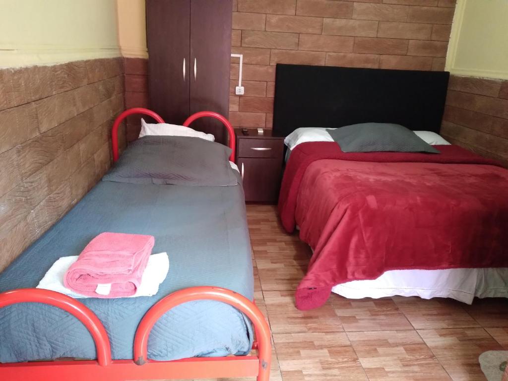 two beds in a room with red and white at HOSPEDAJE DODERA in Gualeguaychú