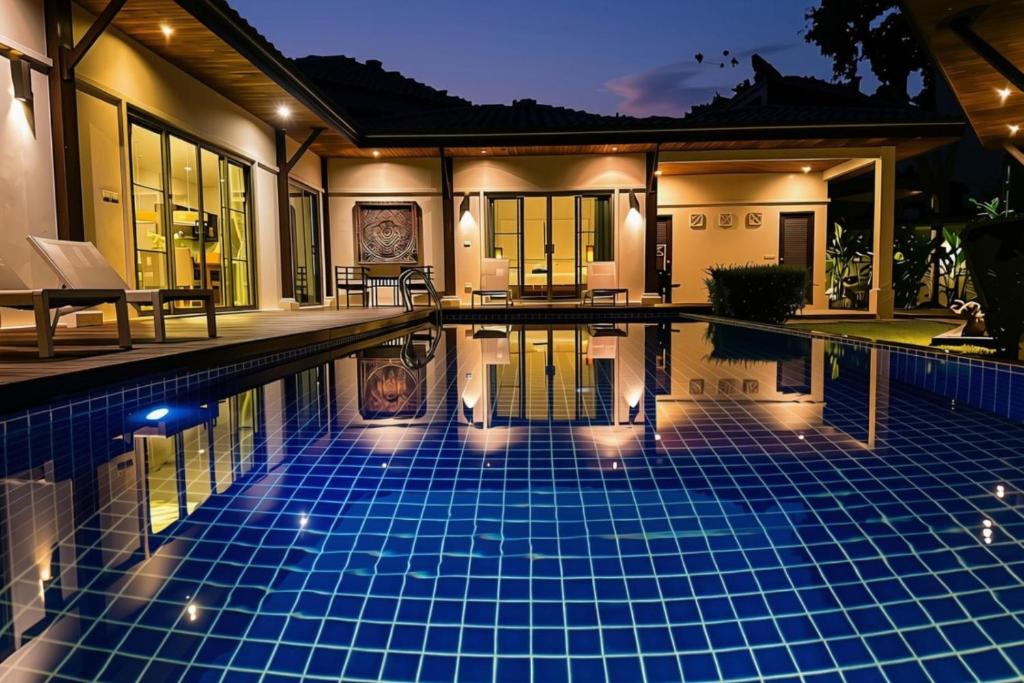 a swimming pool in front of a house at night at Emerald Pool Villa Lush Villa On A Sunny Island in Nai Harn Beach
