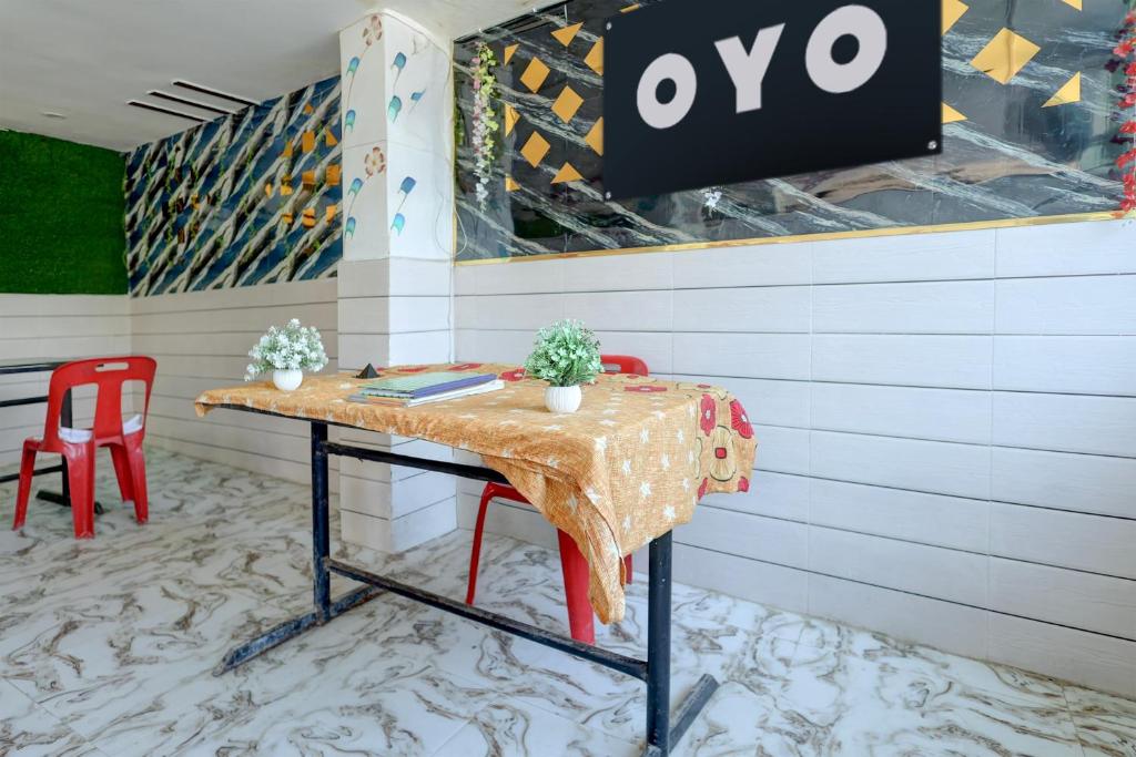 a table with two red chairs and a sign on a wall at Hotel O S.R GRAND HOTEL & RESTAURANT in Kānpur