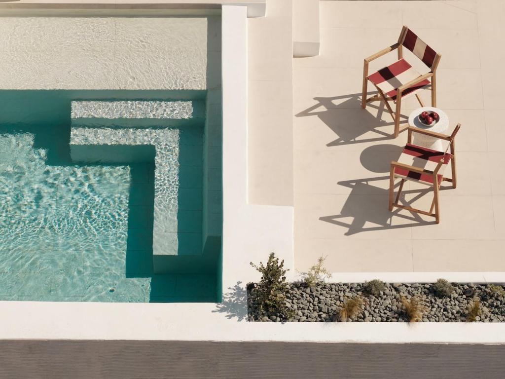 a chair sitting on the side of a building next to a pool at Villa Sol Mare Naousa, Paros in Naousa