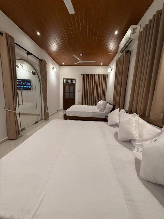 a large white room with two beds and a window at Yalora Villa Kataragama in Kataragama