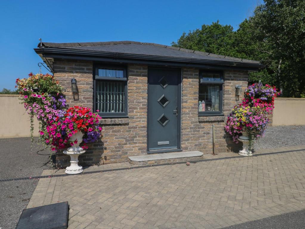 a small brick building with two vases filled with flowers at Annexe Meadows Farm in Swansea