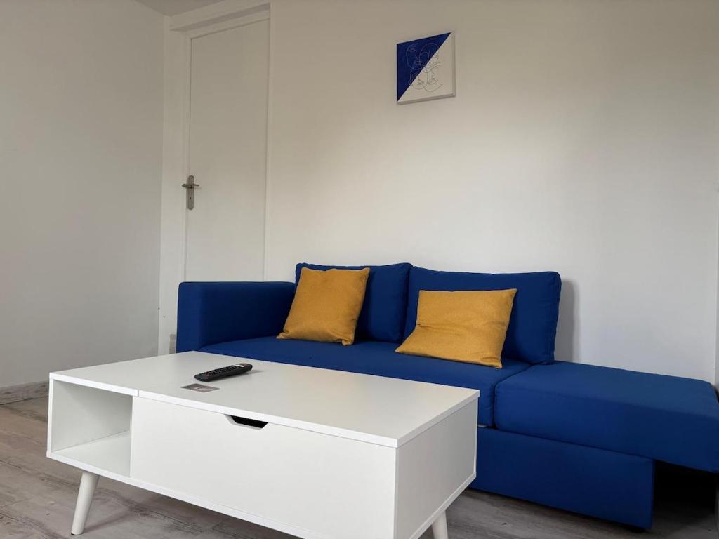 a blue couch with yellow pillows and a white coffee table at Sam's cocoon in Vicq-sur-Nahon