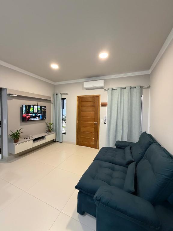 a living room with a blue couch and a tv at Bairro Universtário - Central in Cascavel