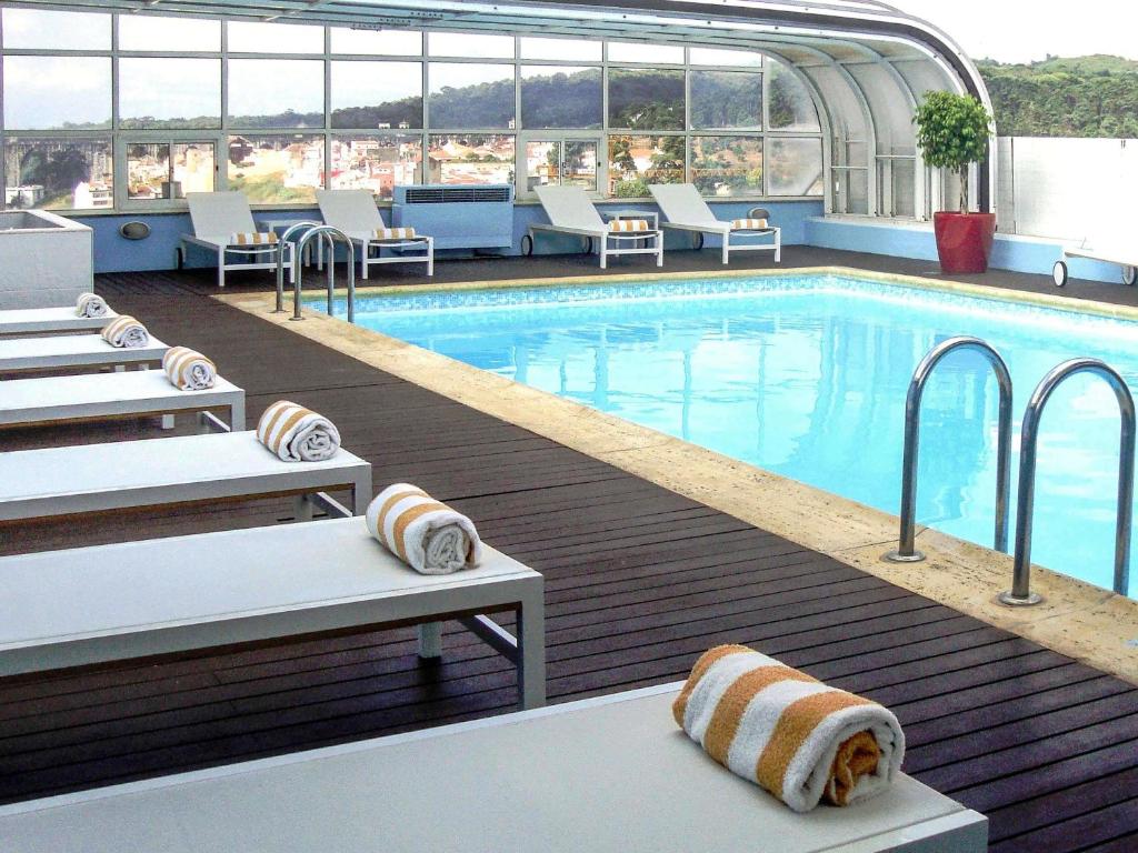 a large swimming pool with lounge chairs and a swimming pool at Hotel Mercure Lisboa in Lisbon