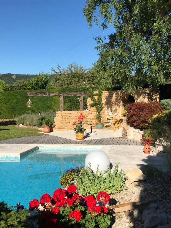 a swimming pool with red flowers in a garden at La Petite Provence in Arbois