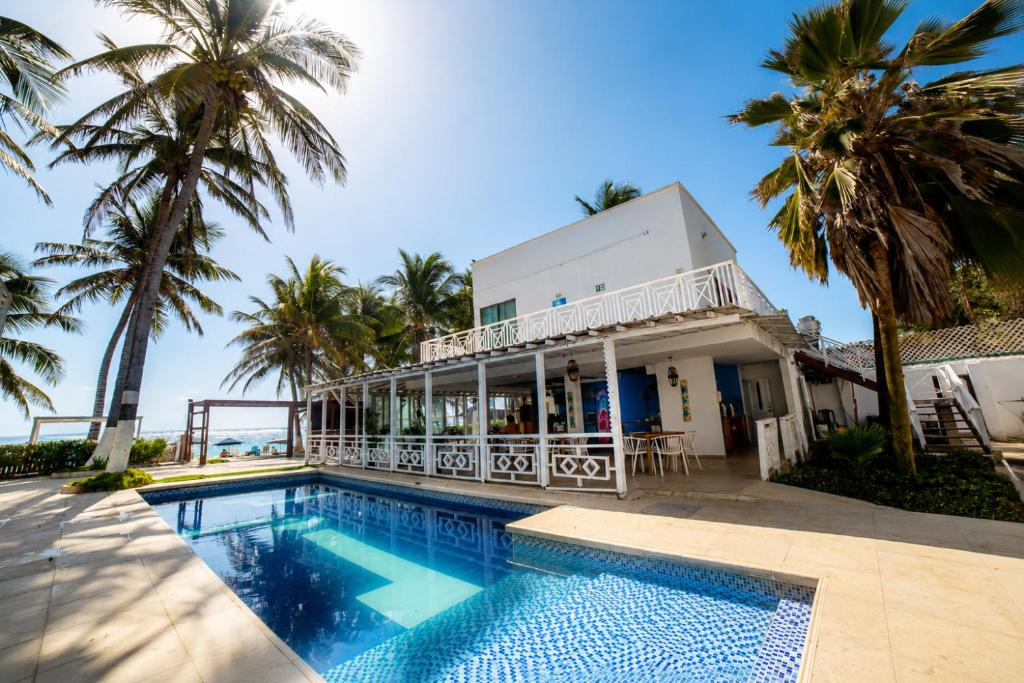 a house with a swimming pool and palm trees at Hotel San Luis Beach House By OxoHotel in San Andrés