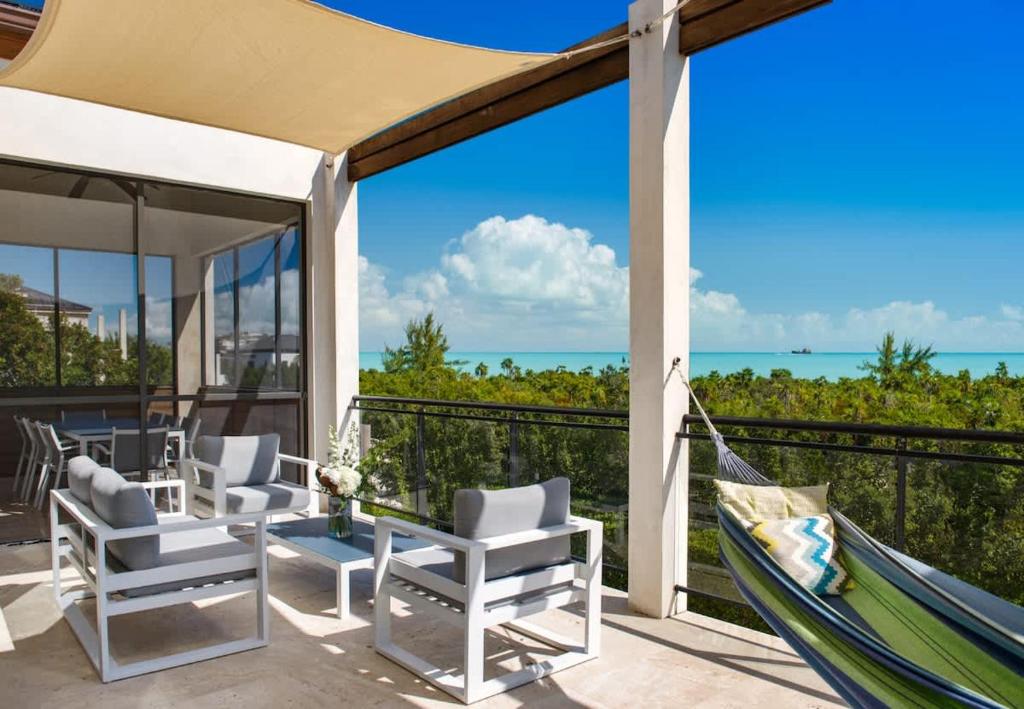 a patio with a hammock and the ocean at Bora 4 BR Villa in Long Bay Hills