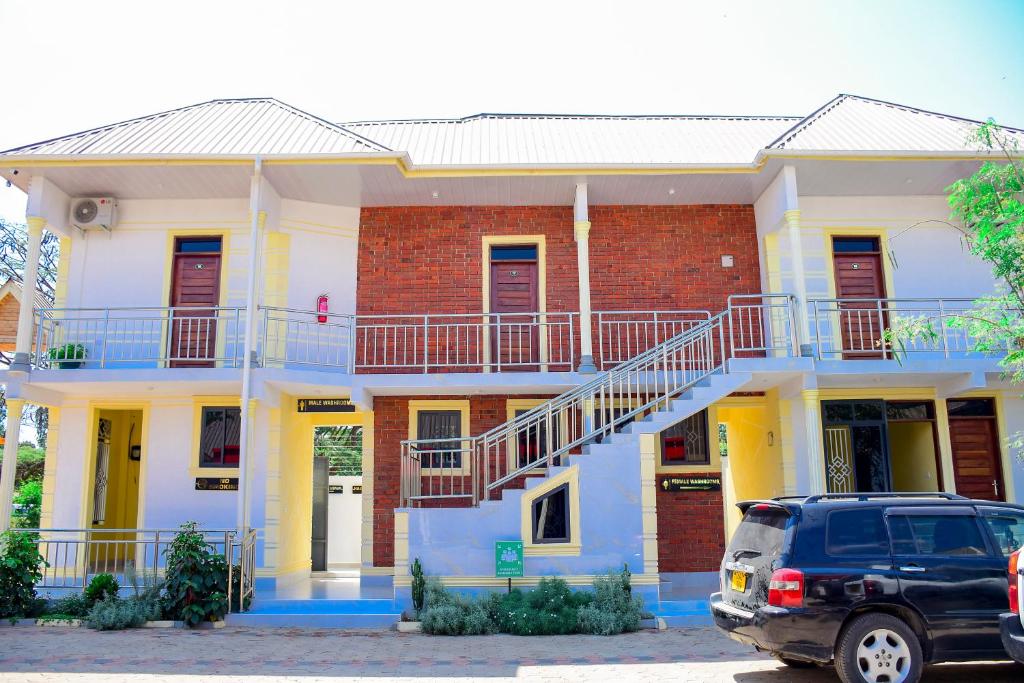 a blue and white house with a car parked in front at JOSEPHINA LODGE Dodoma in Dodoma