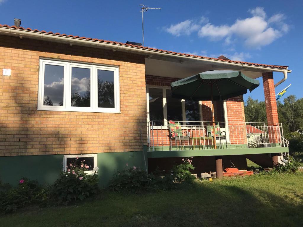 a house with a balcony with a table and an umbrella at Cozy Smalandcottage Alsterfors 23 - towels, bed linen and toiletries provided - in Alsterfors