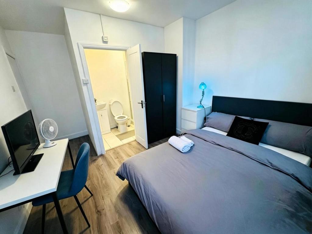 a bedroom with a bed and a desk and a bathroom at Chadwell Heath Rooms in Goodmayes