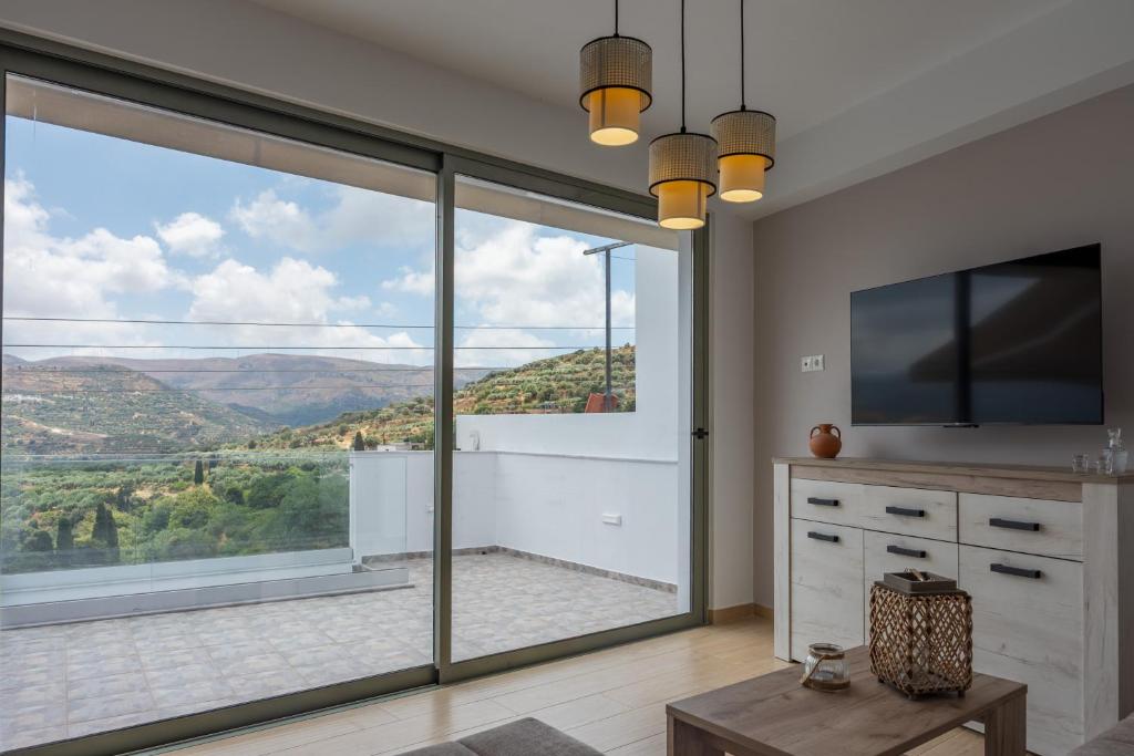 a living room with a large sliding glass door at Cretan View - Valley & Mountains View Sitia in Áyios Yeóryios