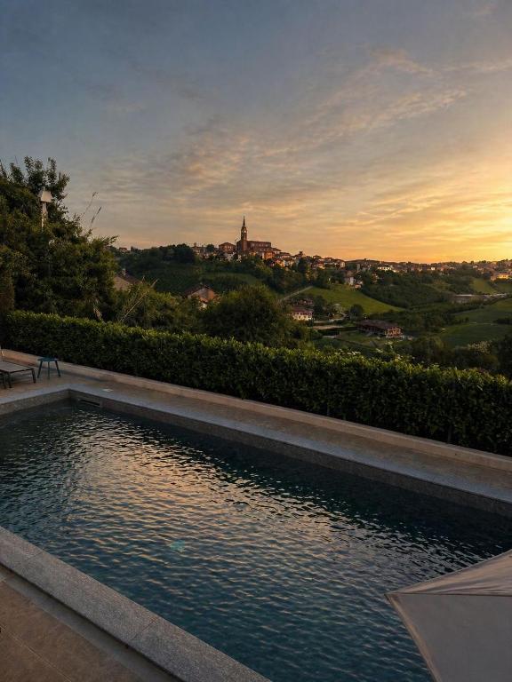 a swimming pool with a sunset in the background at Lange in Priocca