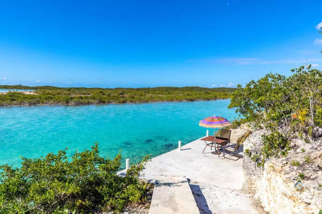 a table and an umbrella sitting on a beach at Breathtaking Chalk Sound Private Pool Sunset Villa in Providenciales