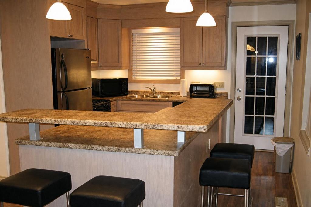 a kitchen with a counter with stools and a refrigerator at JACKSON HOLE HIDEAWAY in Jackson