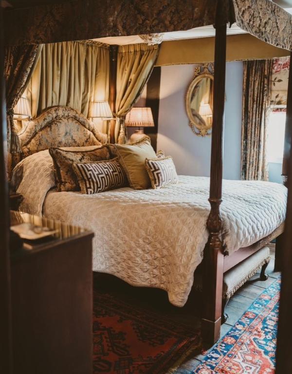 a bedroom with a canopy bed with pillows on it at St Columbas Boutique BnB in Weobley