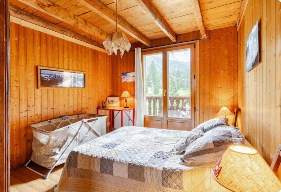 a bedroom with a bed in a room with wooden walls at Chambre 2 balcon in Mont-Saxonnex