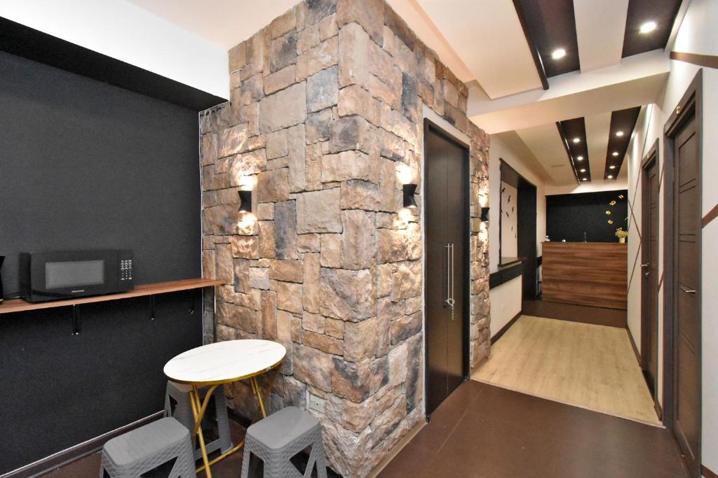 a stone wall in a hallway with a table and stools at Dur baca guest house in Yerevan