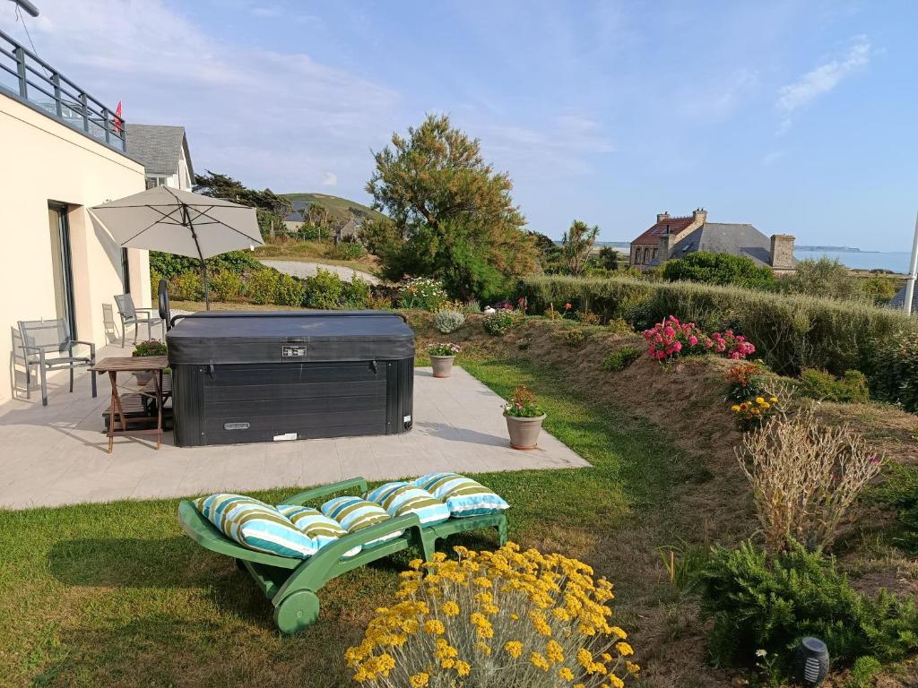 a garden with a bench and an outdoor grill at Chez ALAIN & PATRICK in Vauville