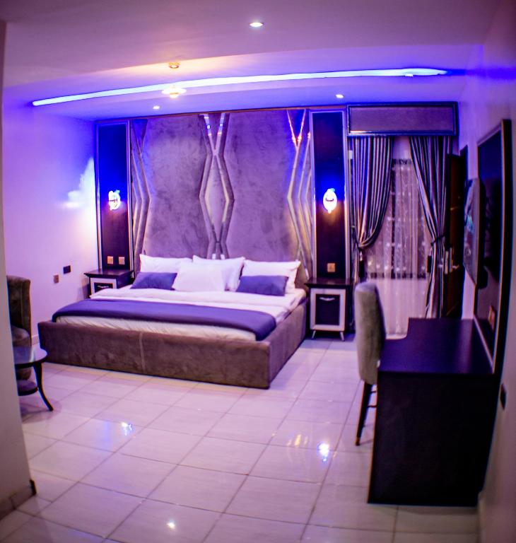 a bedroom with a large bed and a desk at Pretelia Hotel in Warri