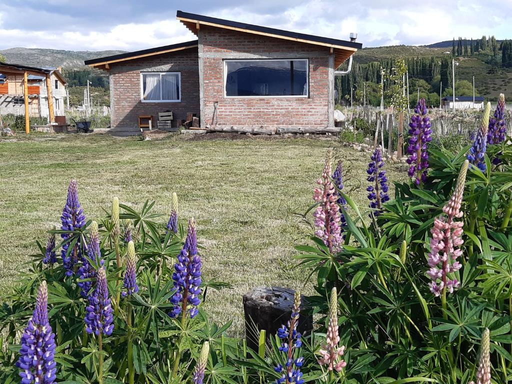 a garden with purple flowers in front of a house at CASA Los Tres Picos in Cholila