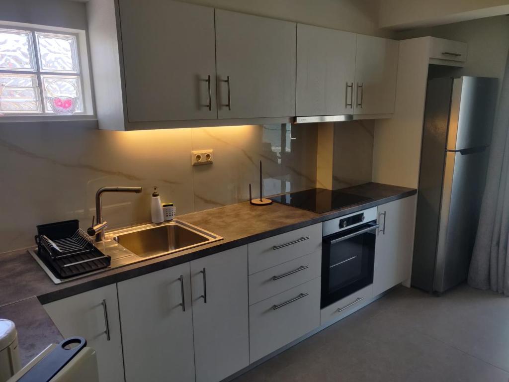 a kitchen with white cabinets and a sink and a refrigerator at Fyki sea view apartment in Vlikhón