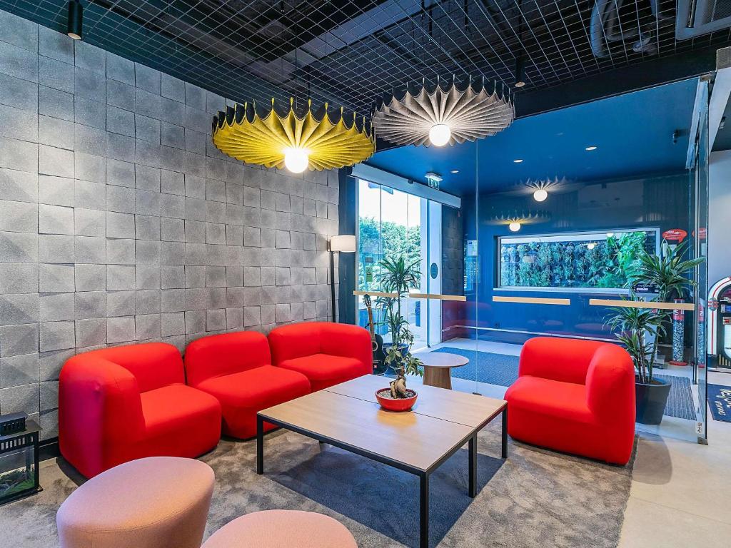 a waiting room with red chairs and a table at Hotel ibis Lisboa Alfragide in Lisbon