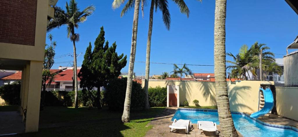 a backyard with a swimming pool with palm trees at Pousada Peruibe in Peruíbe