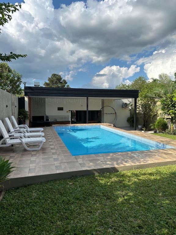 a swimming pool with chairs and a house at Vivíana Hause Hospedaje in Cambyretá