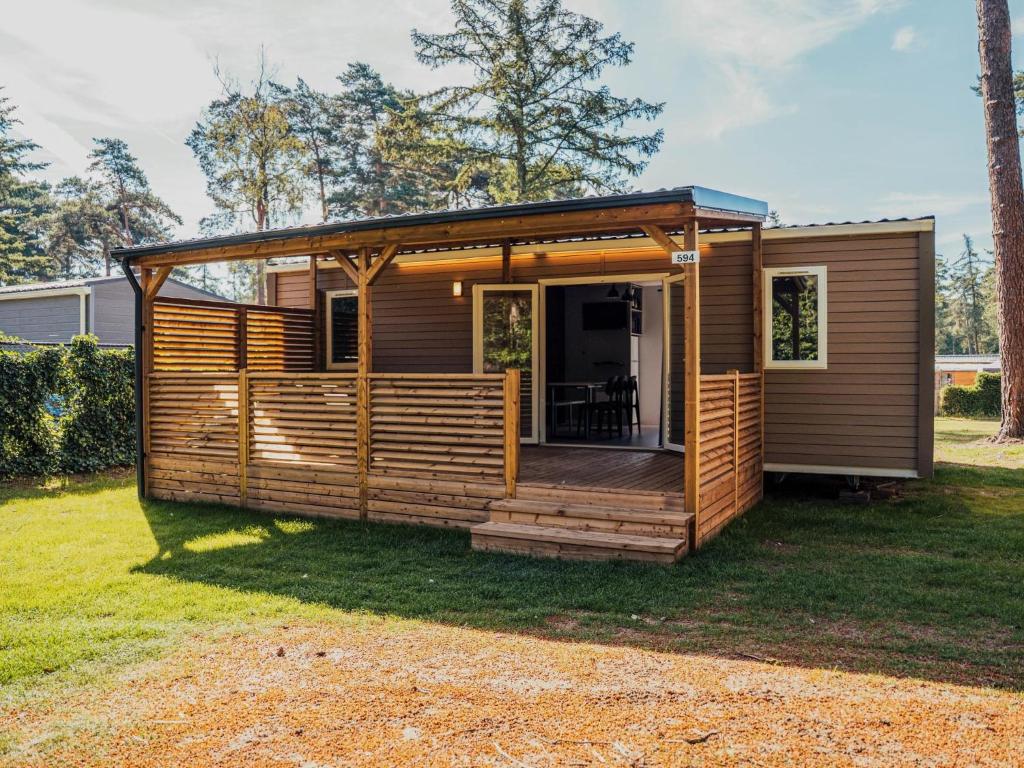a tiny house with a deck in a yard at Timber-Lodge in Vessem