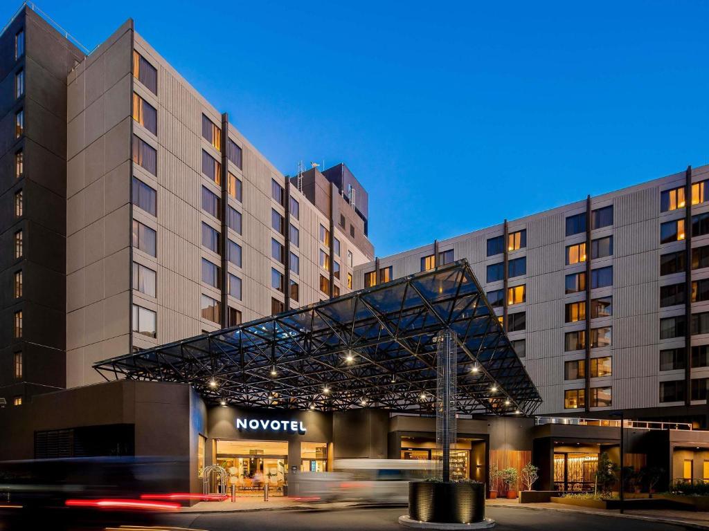 a car driving past a hotel with a building at Novotel Sydney International Airport in Sydney