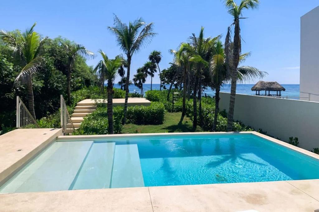 a swimming pool with a view of the ocean at Chic Beachfront Condo Ocean View Rooftop Pools in Akumal