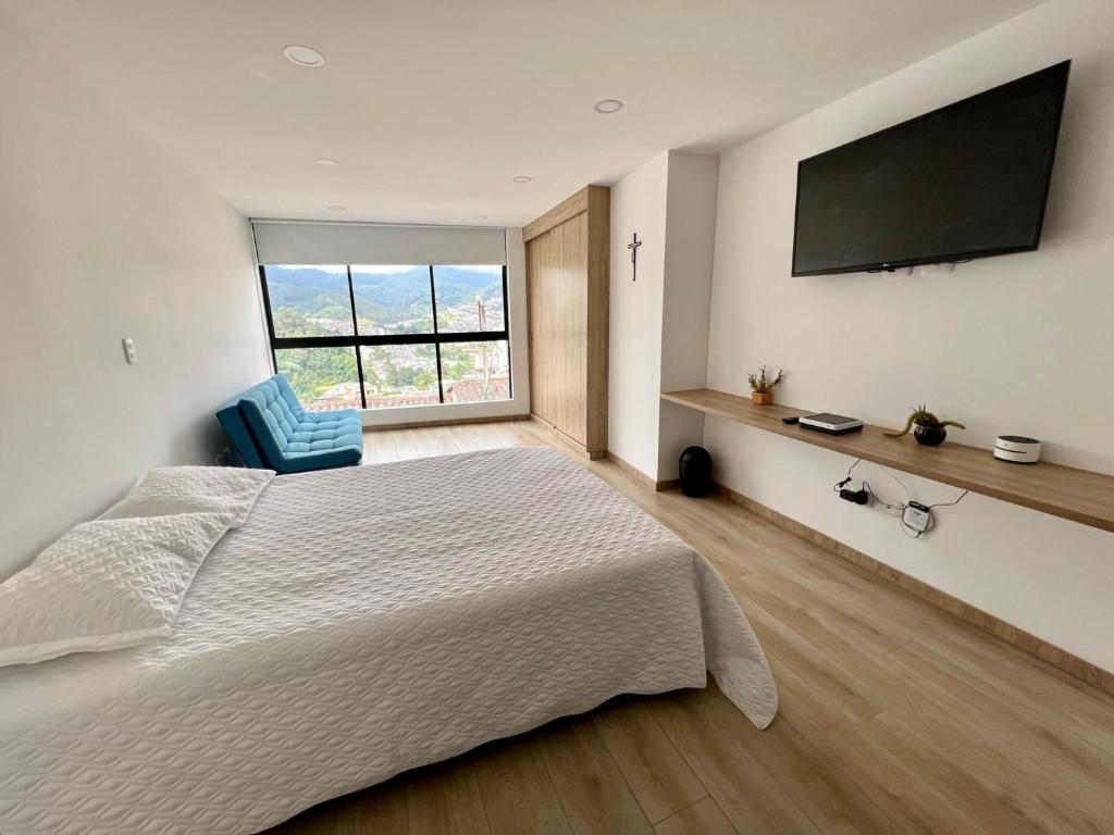 a bedroom with a large bed and a large window at HOSTARA EDIFICIO CAPITALIA, El Cable, Manizales in Manizales