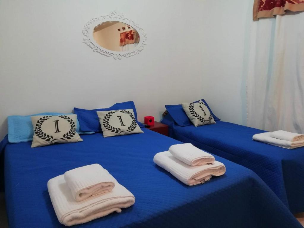 two beds in a room with blue sheets and pillows at Cabaña con balcón luminosa in Ushuaia