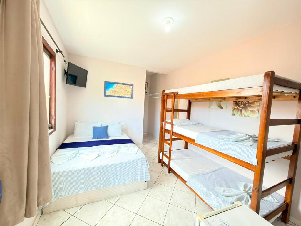 two bunk beds in a room with a tv at Pousada Azul do Mar by BlueOcean in Arraial do Cabo