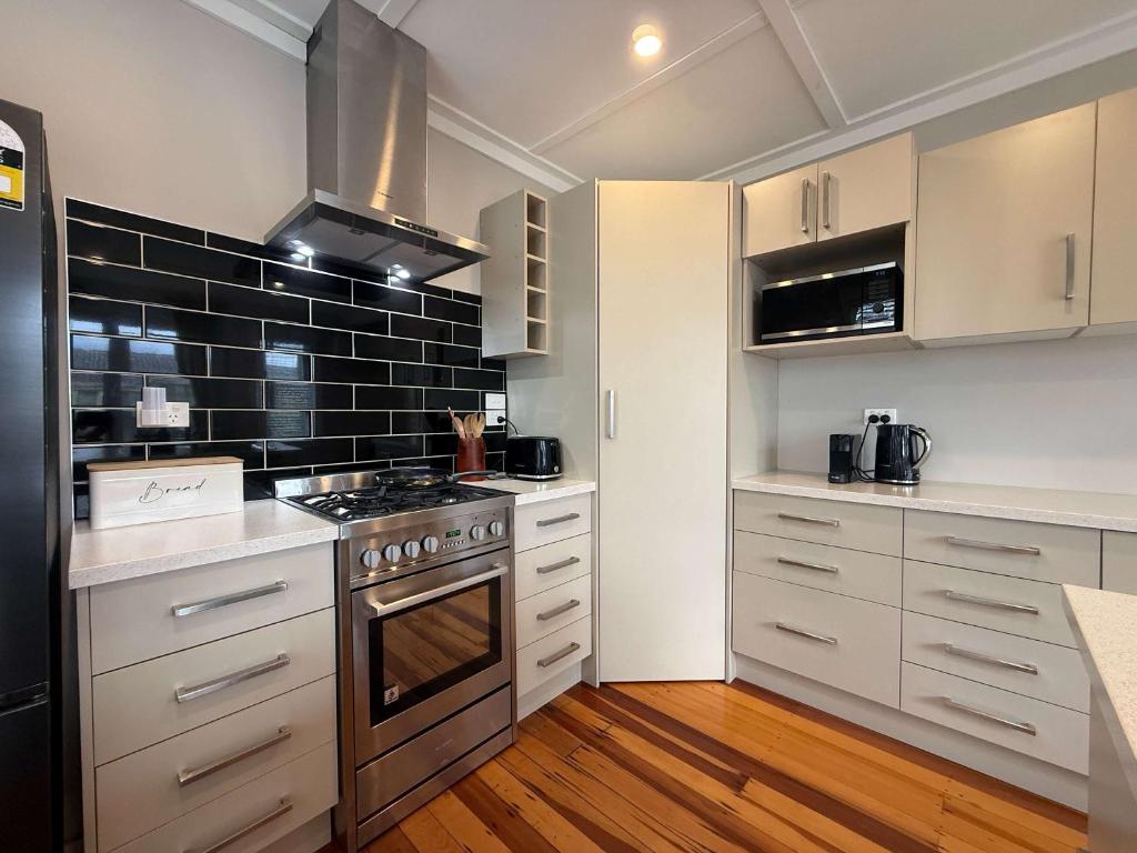 a kitchen with white cabinets and a stove top oven at Maison Millie - Central Pet-Friendly Sleeps 4 in Rotorua