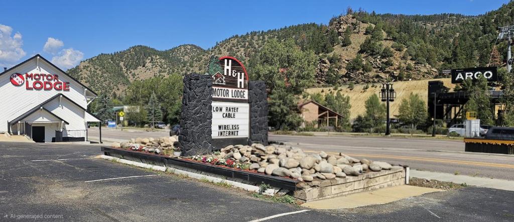 a sign in a pile of rocks in a parking lot at H&H Motor Lodge in Idaho Springs