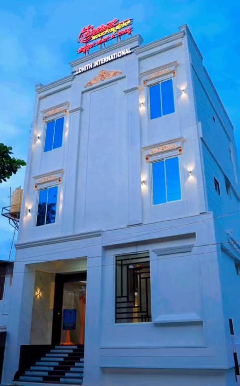 a white building with stairs in front of it at Lohith International in Shimoga