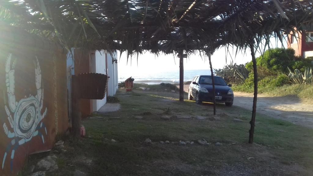 un coche aparcado frente a una casa con el océano en Complejo la Cuevita en Mar del Sur