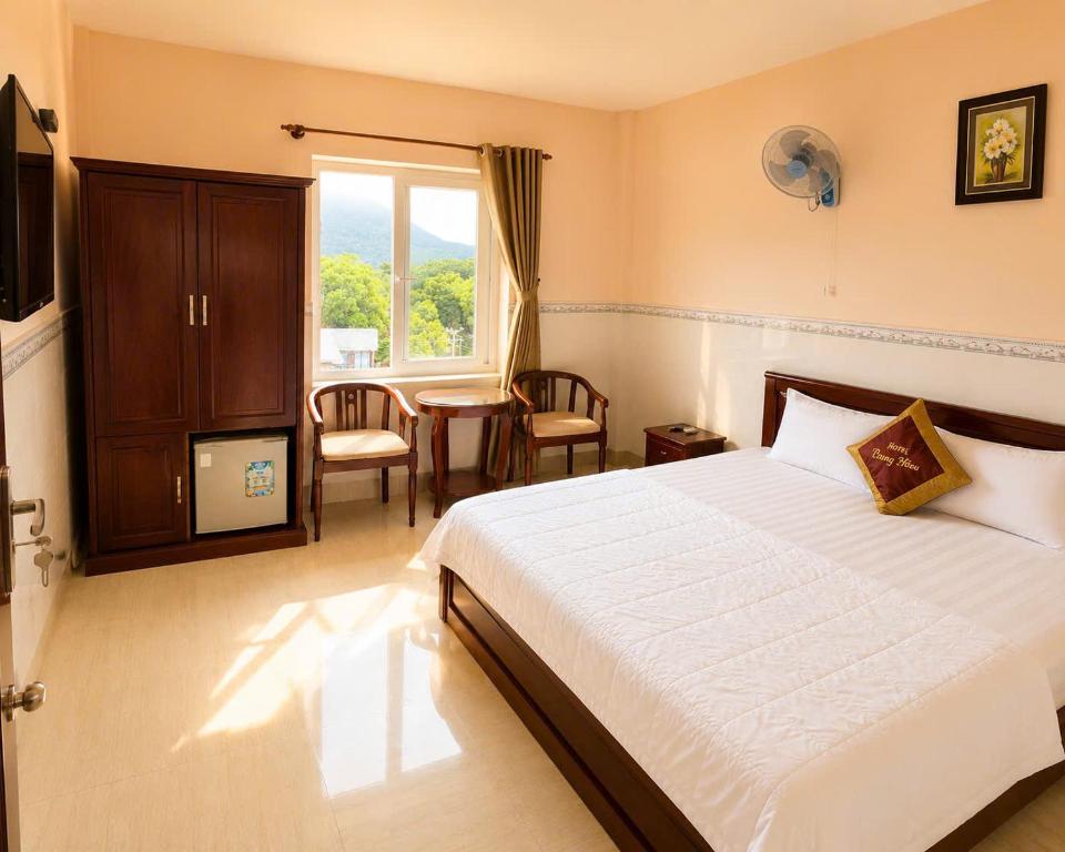 a bedroom with a bed and a table and a window at Trung Hậu Hotel Côn Đảo in Con Dao