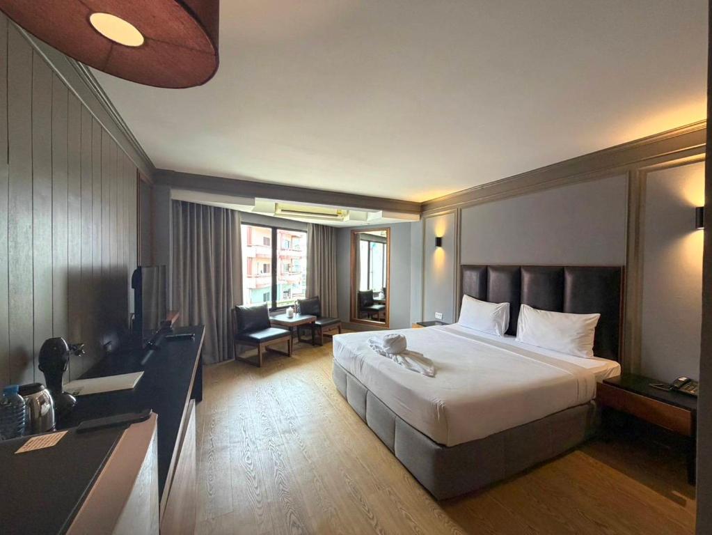 a hotel room with a large bed and a desk at Marine Plaza Hotel Pattaya in Pattaya South