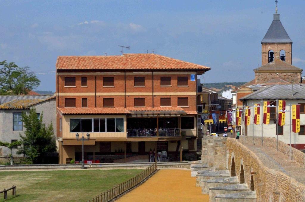 a building with a clock tower in a town at Hostal Don Suero de Quiñones in Hospital de Órbigo