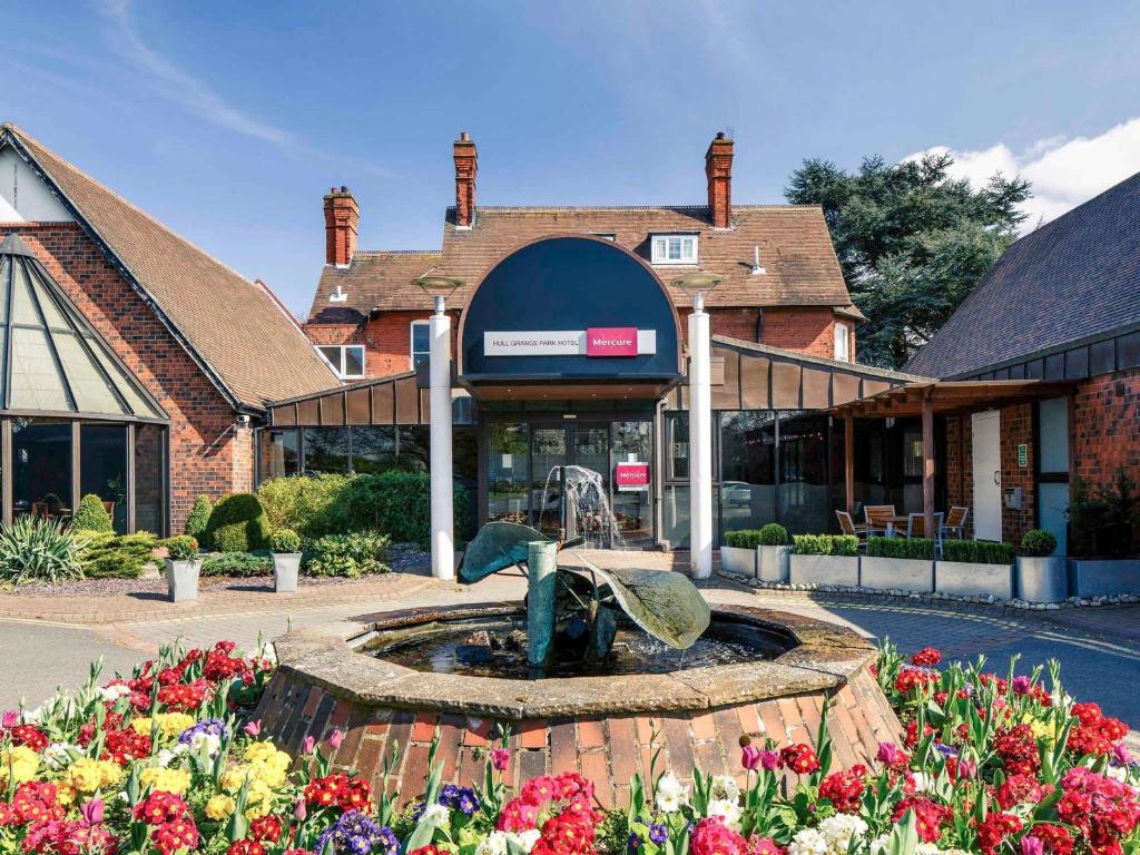 a building with a fountain in front of a store at Mercure Hull Grange Park Hotel in Hull